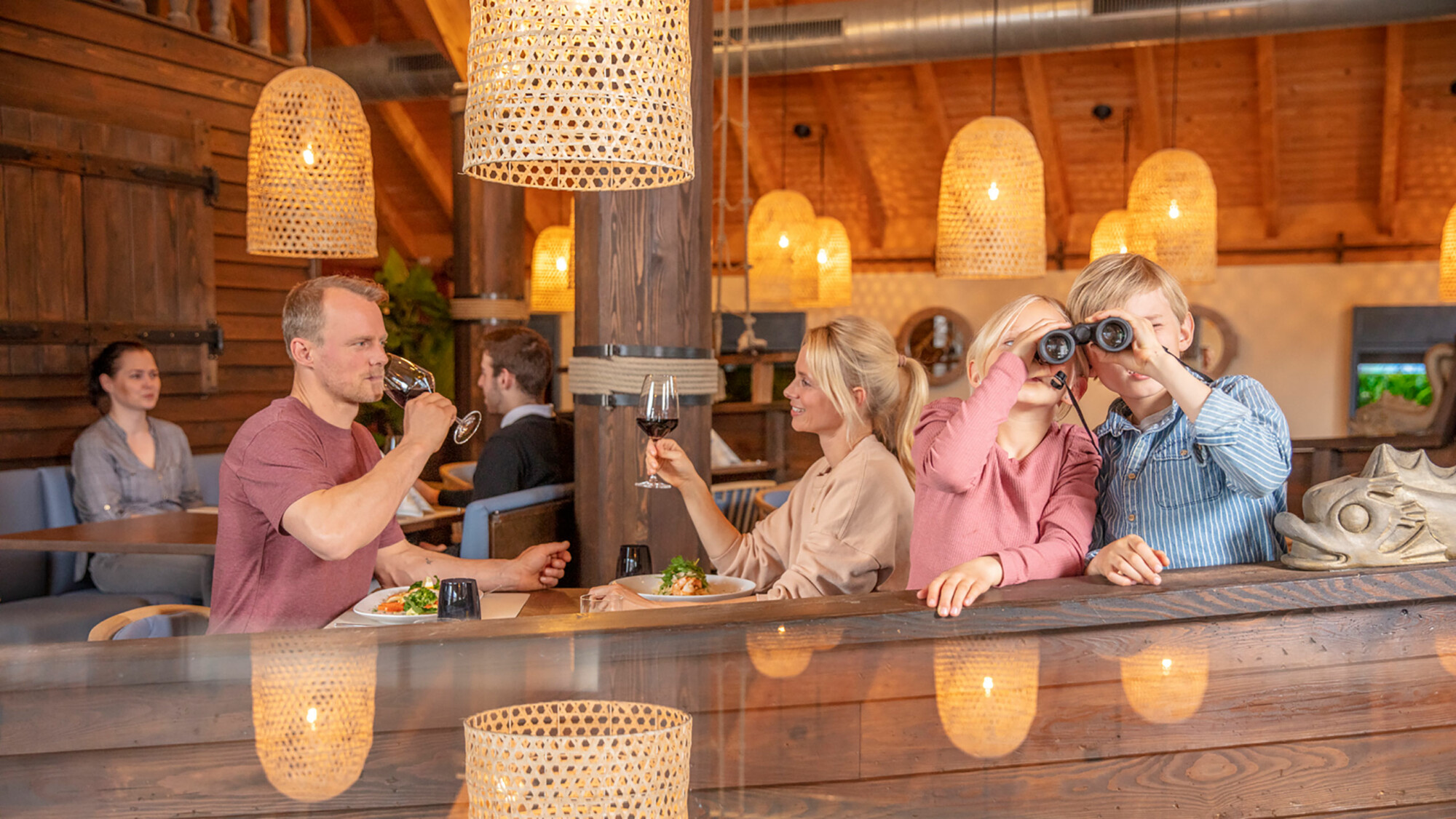 Familie im Restaurant Göhren Lebbin und Kinder gucken durch ein Fernglas zum Familienresort