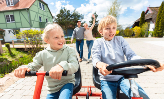 Geschwister fahren mit dem Kettcar durch das Familienresort Fleesensee