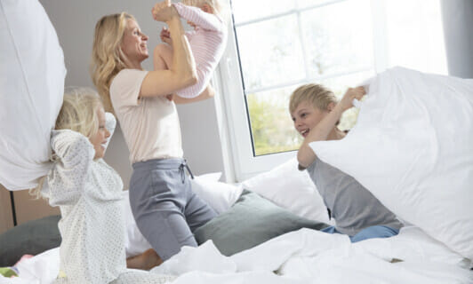 Familie macht Kissenschlacht im Apartment am See