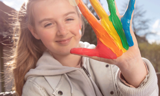 Kind mit Fingerfarben an der Hand
