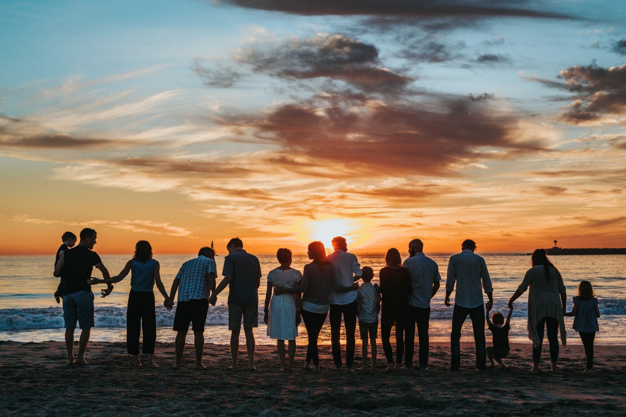 großes Familienfoto beim Sonnenuntergang am Strand