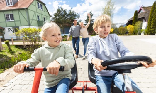 Geschwister fahren mit dem Kettcar durch das Familienresort in Mecklenburg Vorpommern