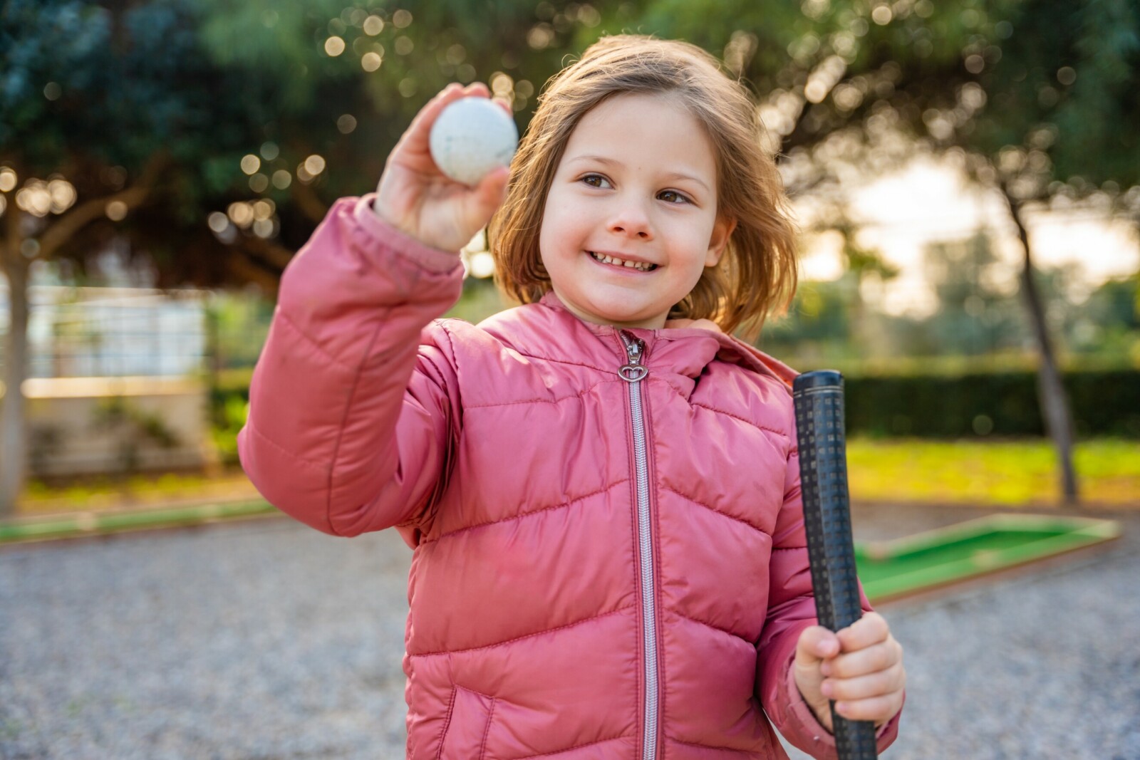 Kleines Mädchen hält Golfball in die Luft