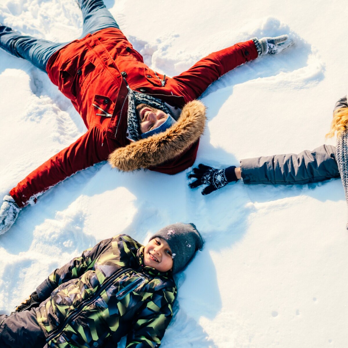 Drei Kinder liegen im Schnee